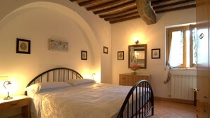 A bedroom with a bed, nightstand, dresser, and a window with a view. - La Dolce Collina (Castiglione del Lago)