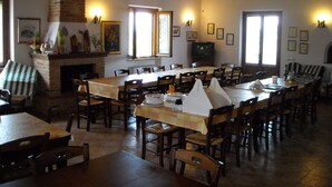 A dining area with a long table, multiple chairs, a fireplace, and framed pictures on the walls. - La Dolce Collina (Castiglione del Lago)