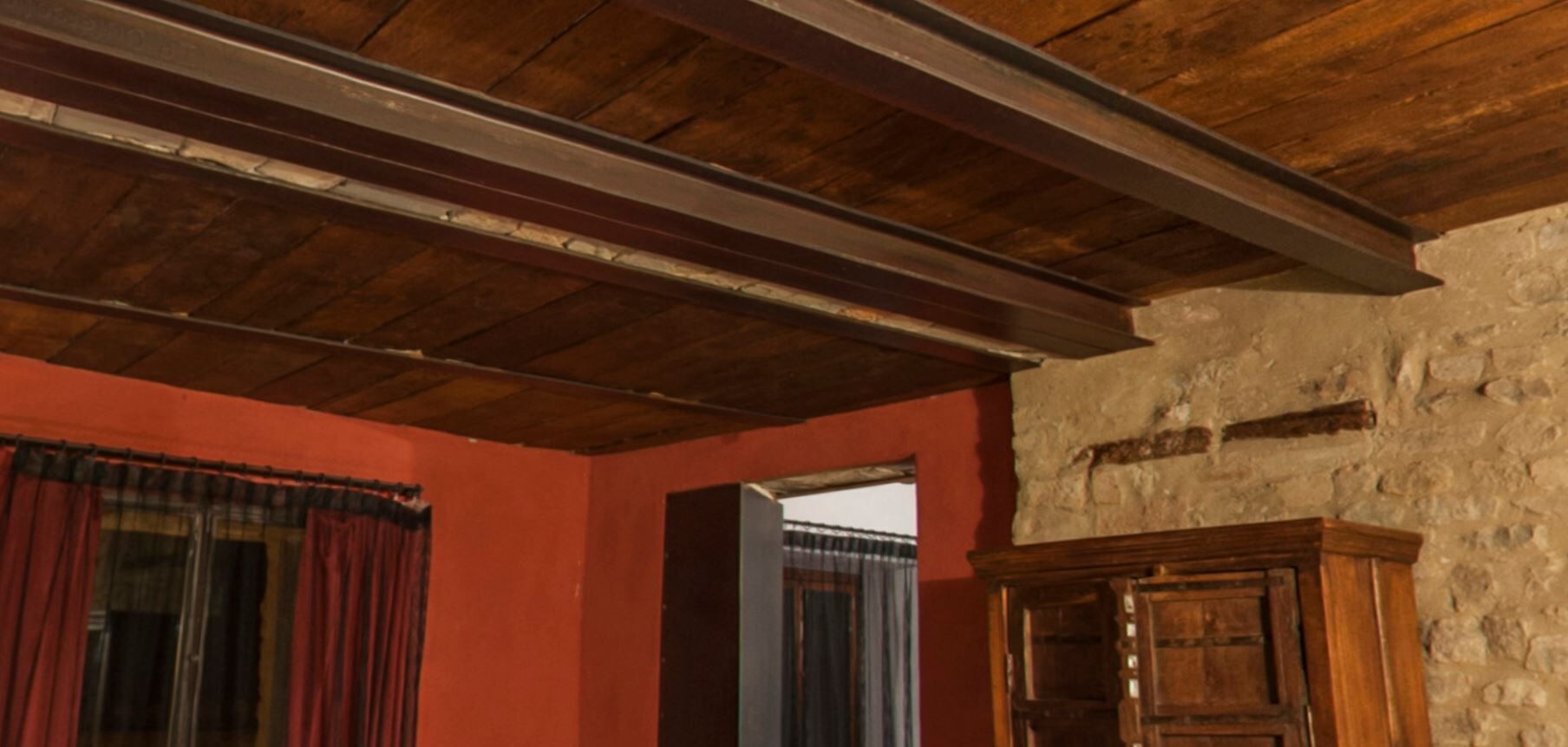 Una stanza con soffitto in legno, parete rossa e un armadietto in legno.