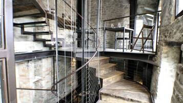 A spiral staircase with metal railings, leading to a seating area with tables and chairs.