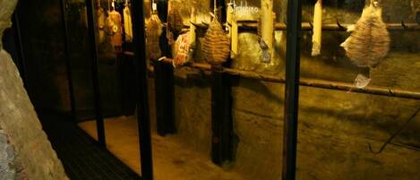 A dimly lit underground room with hanging bags and a metal staircase.