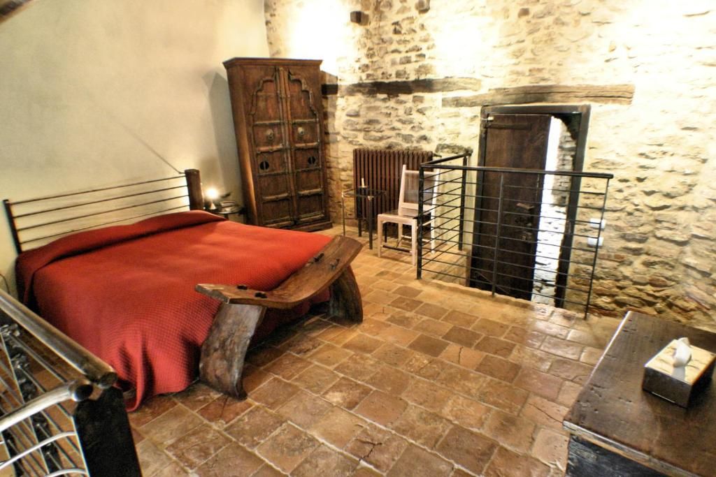 Ein rustikaler Raum mit einem Bett, einem Holzkabinett, einem Heizkörper und einer Steinwand.