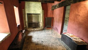 A narrow hallway with a stone floor, a fireplace, and a radiator. - Le Case Della Saracca (Monforte d'Alba)