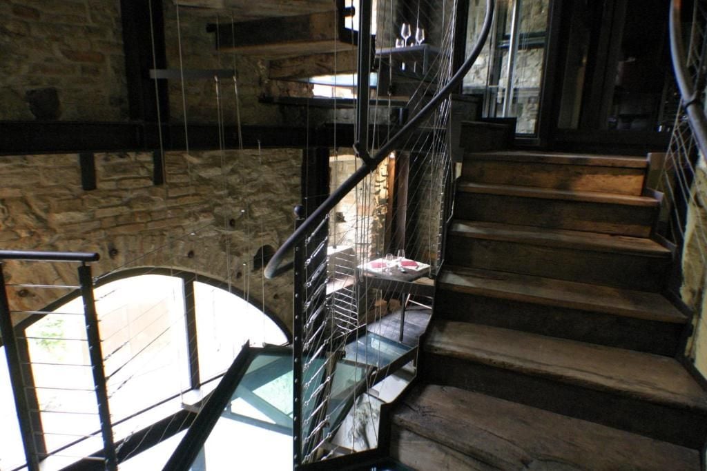 A spiral staircase with a glass balustrade leading to a lower level.