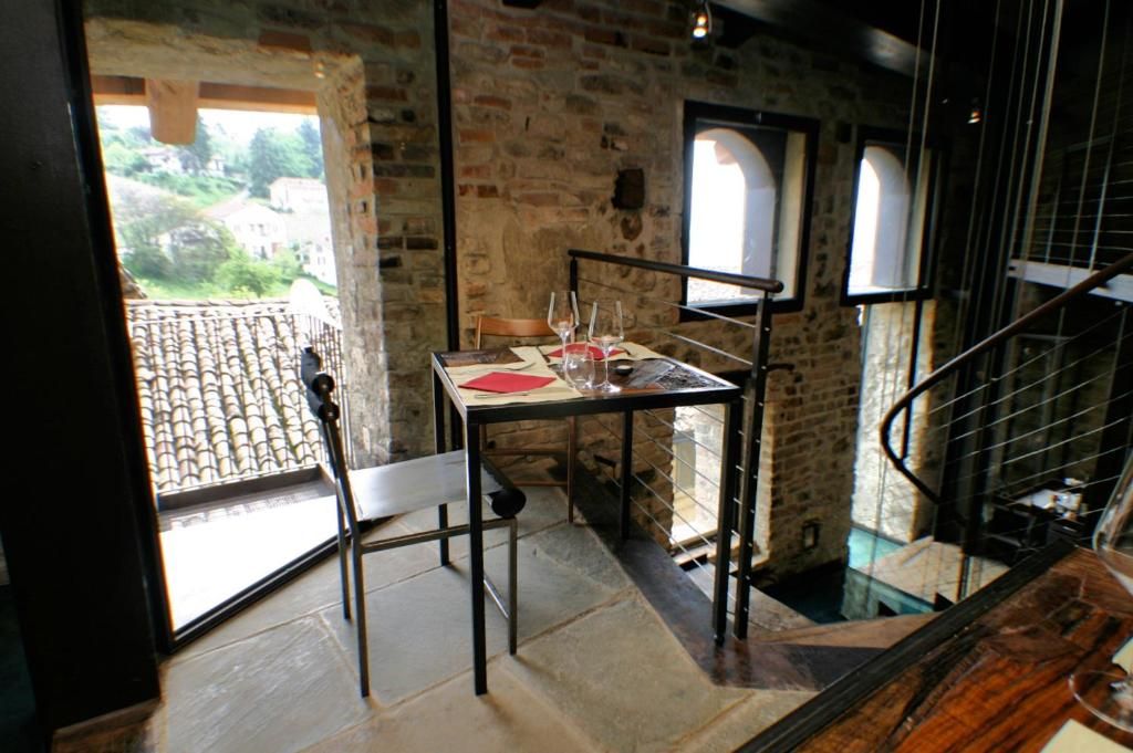 A dining area with a table set for two, a chair, and a view of a courtyard through a window.