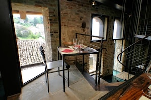 Un área de comedor con una mesa preparada para dos, una silla y vistas a un patio a través de una ventana.