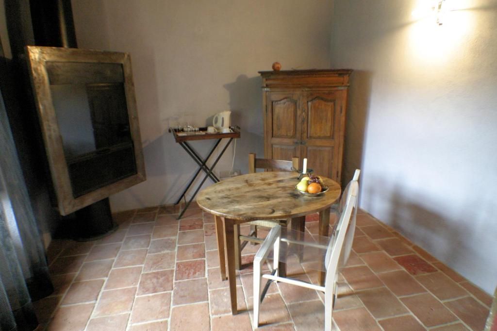 A room with a tiled floor, a wooden table with a chair, a cabinet, and a framed picture on the wall.