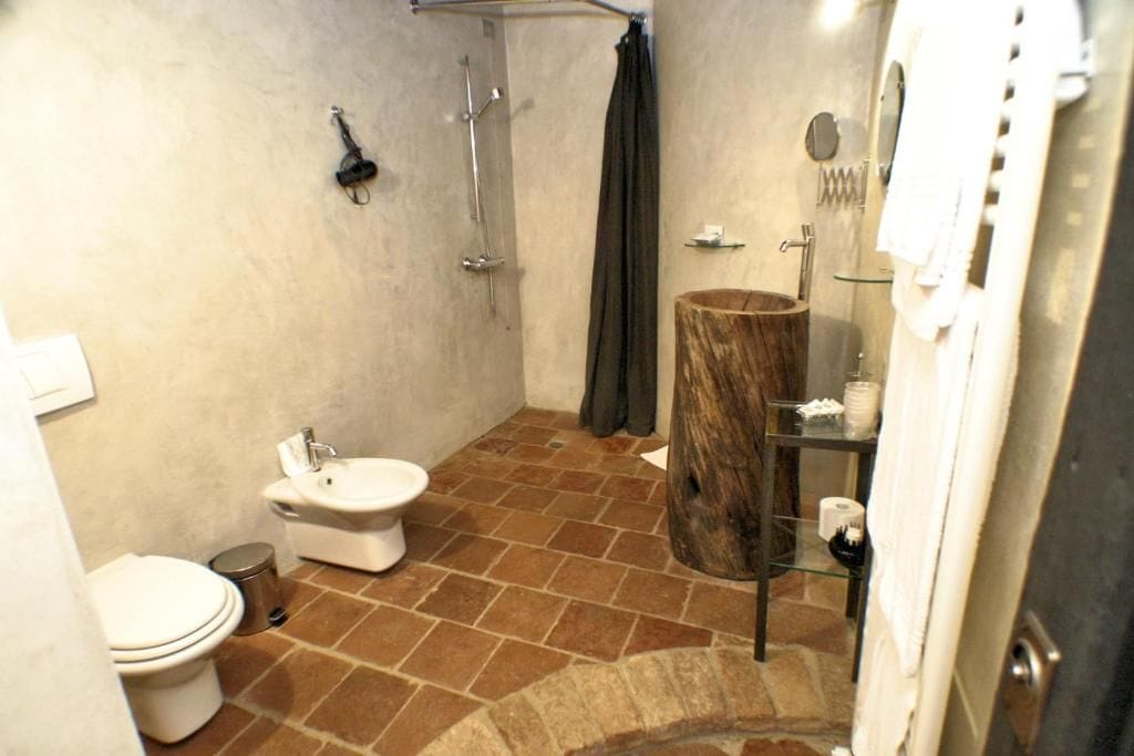 Un baño con inodoro, bidé, ducha y tocador de madera.