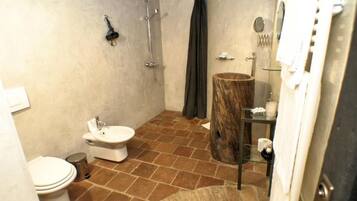 Een badkamer met toilet, bidet, douche en een houten wastafelmeubel.