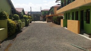 A residential street with houses on both sides, a gravel driveway, and a clear sky. - Genesis Guest House (Naivasha)
