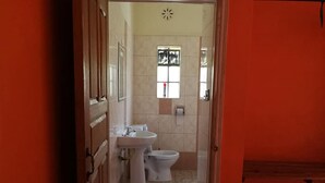 A narrow hallway leading to a bathroom with a sink, toilet, and window. - Genesis Guest House (Naivasha)