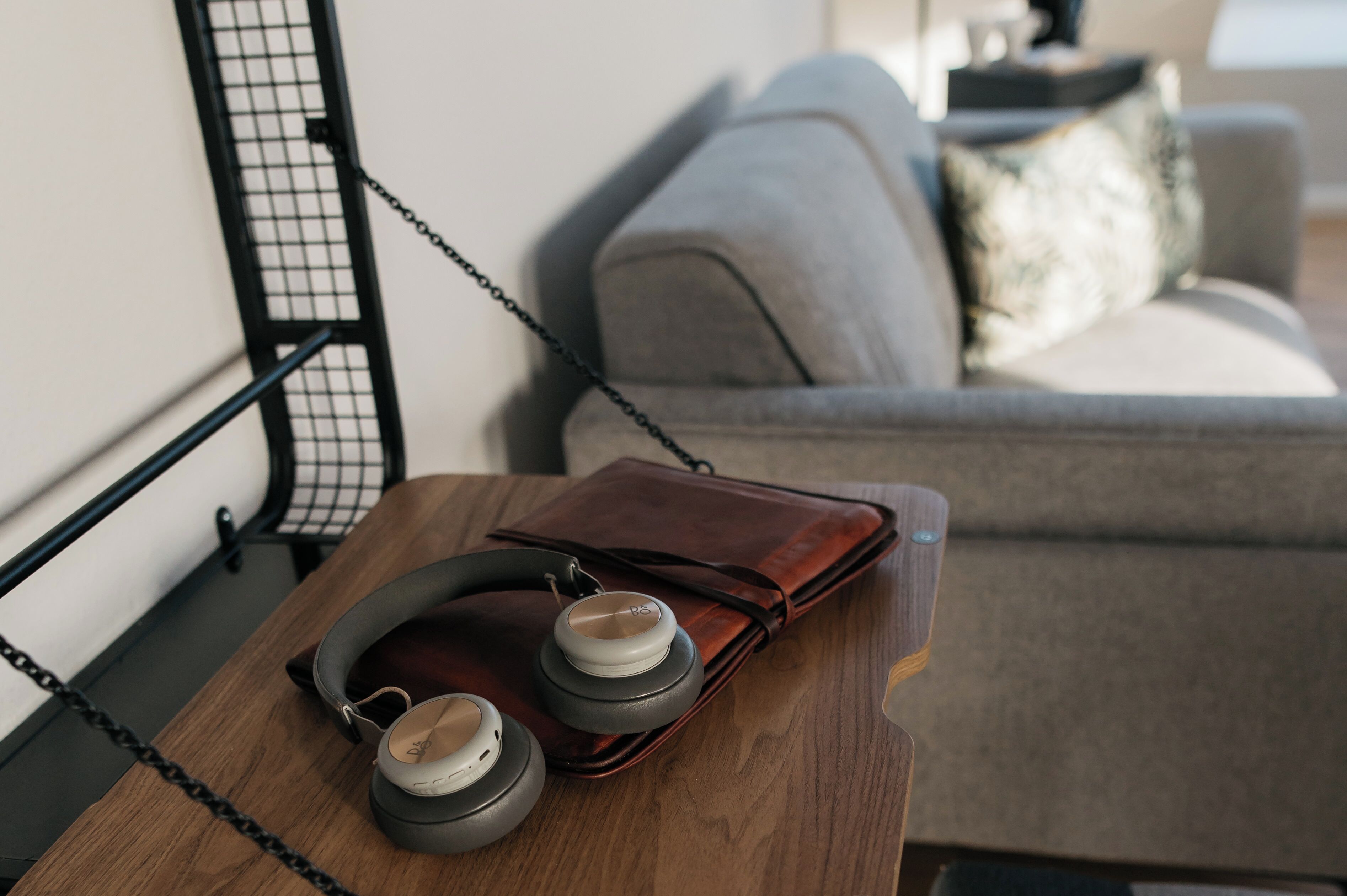 A wooden table with a pair of headphones and a brown leather wallet.
