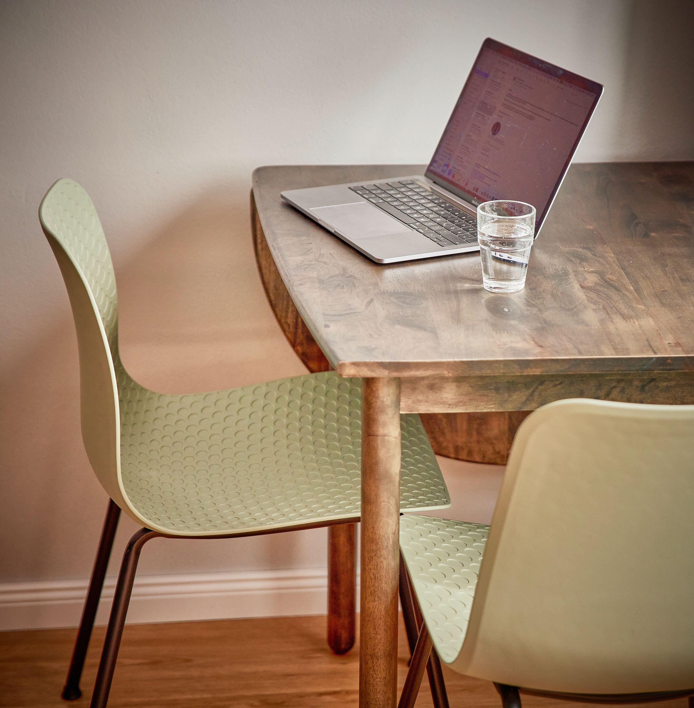 Une table en bois avec un ordinateur portable et un verre d’eau.
