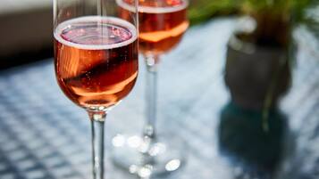 Two glasses of red wine on a glass table with a blurred background.