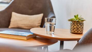 A round wooden table with a glass of water, a book, and a small potted plant.