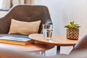 Ein runder Holztisch mit einem Glas Wasser, einem Buch und einem kleinen Topfpflanzen.