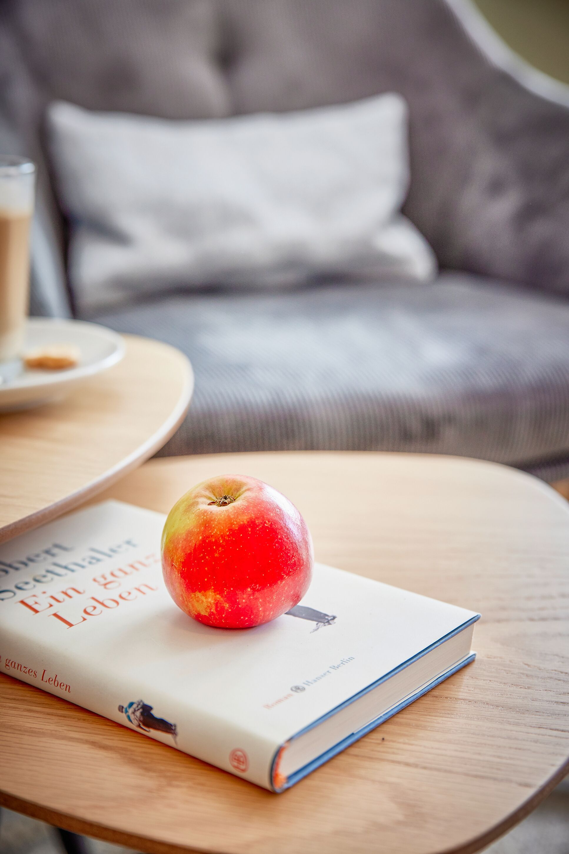 Een boek met de titel 'Ein ganzes Leben' op een ronde houten tafel, met een appel erbovenop.