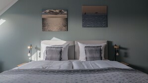 Een slaapkamer met een bed, twee aan de muur bevestigde schilderijen en bedlampen.