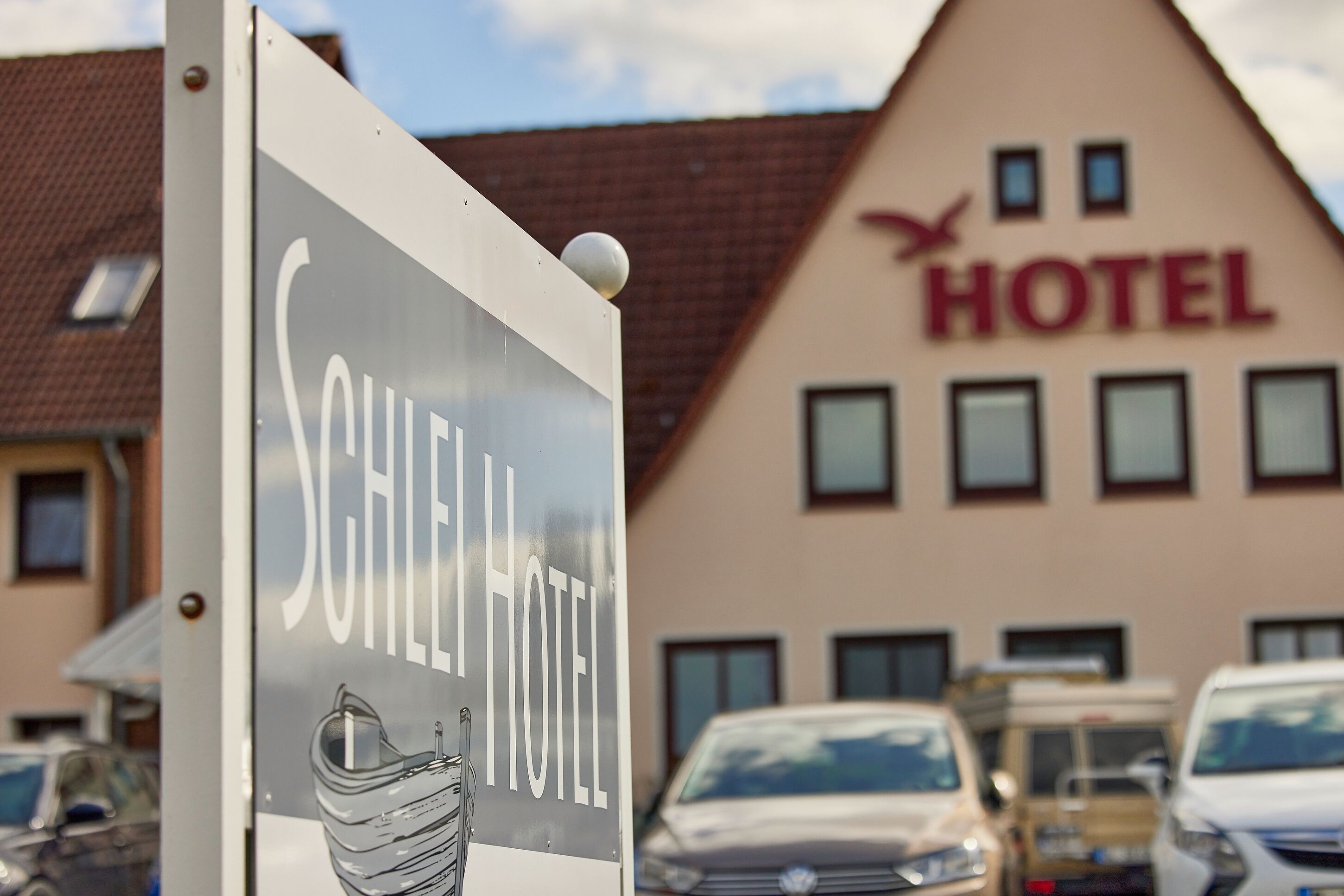Et hotelskilt med et moderne design, der viser en stiliseret fugl og ordet "HOTEL" i tydelig skrift.
