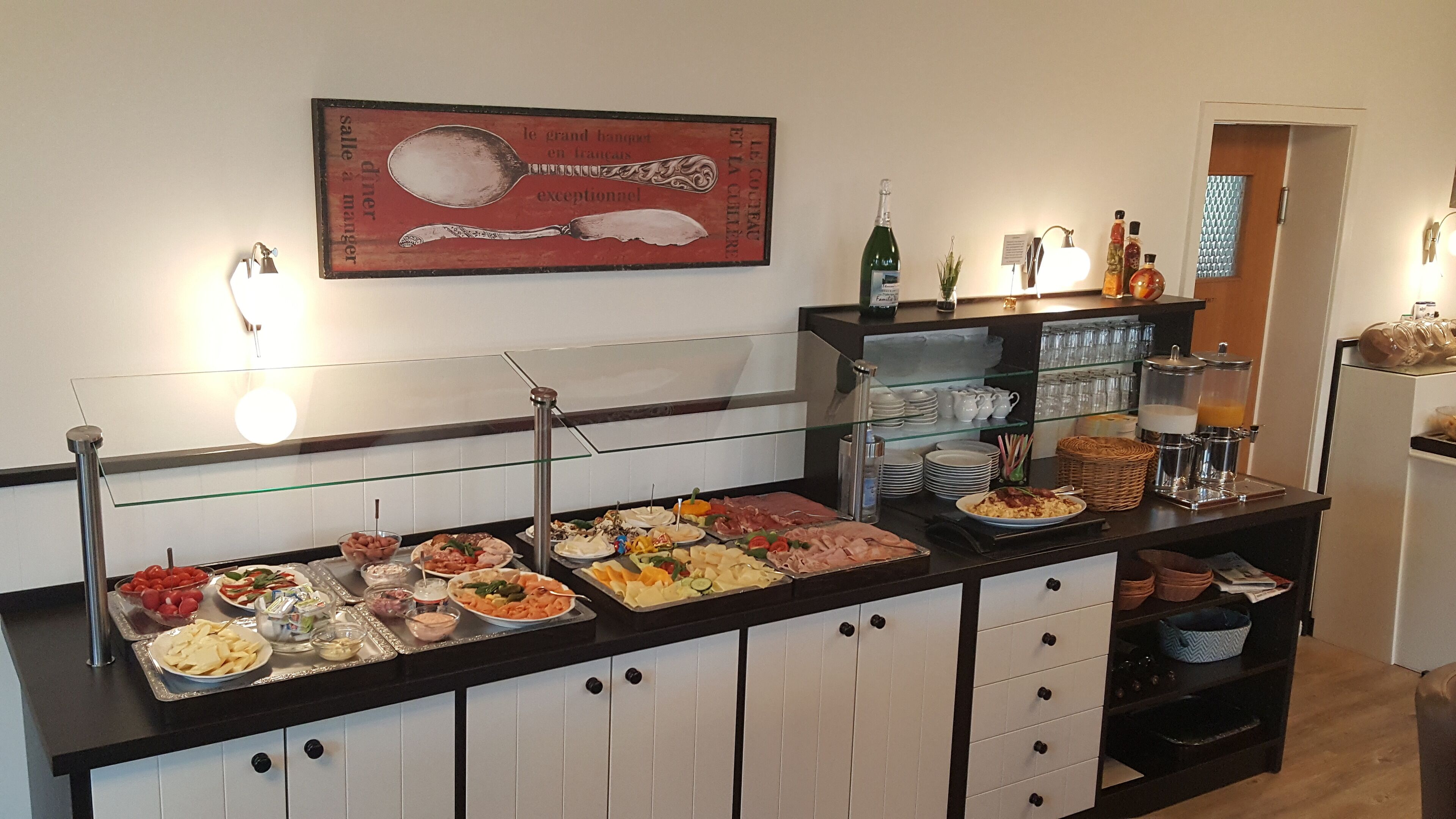A buffet with various food items, a wine bottle, and a coffee machine.