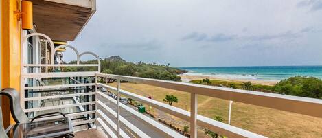A balcony with a view of the beach and ocean.