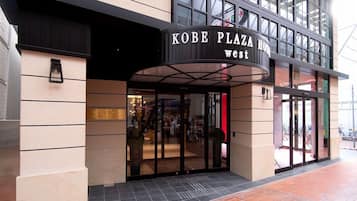 L'ingresso dell'Hotel Kobe Plaza, dal design moderno, con una pensilina curva e ampie porte in vetro.