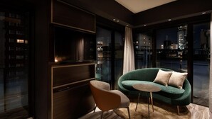 Una sala de estar moderna con un sofá verde, una mesita redonda y un televisor montado en un mueble de madera oscura.