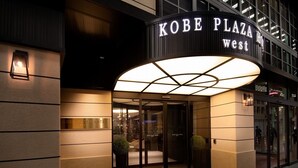 Exterior del Hotel Kobe Plaza West, con un llamativo letrero iluminado, una entrada de vidrio y una fachada bien iluminada.