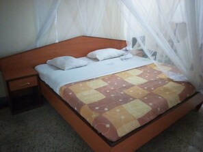 A bed with a wooden headboard, white bedding, and a mosquito net.