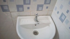 A white bathroom sink with a single faucet and a drain.