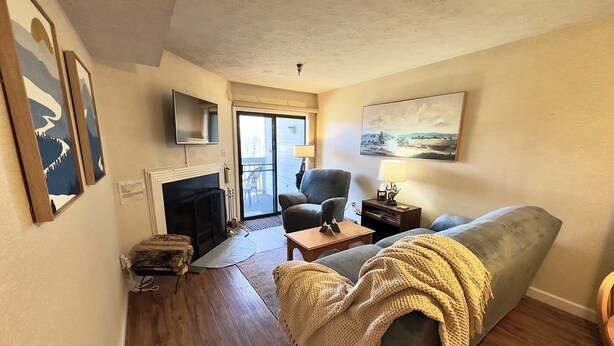 Ein Wohnzimmer mit Kamin, einer Couch, einem an der Wand montierten Fernseher und einem Gemälde über der Couch.