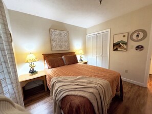 Quarto com cama, duas mesas de cabeceira com luminárias, um guarda-roupa e uma parede decorada.