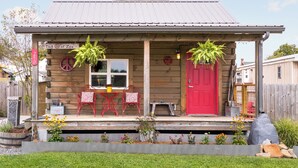 En træhytte med rødlakeret dør, en veranda med røde stole og et skilt, der siger "Tiny Peace of Zen".