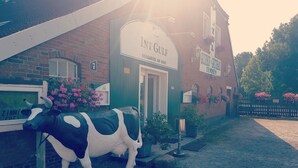 A building with a sign reading "Int Gulf Biergarten am Haus" and a cow statue in front. - Gulfhof (Emden)