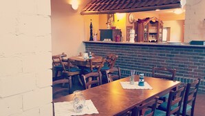 A cozy dining area with wooden tables and chairs, a brick wall, and a tiled ceiling. - Gulfhof (Emden)