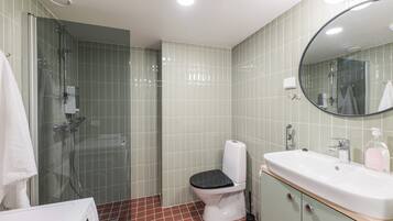 A bathroom with a glass-enclosed shower, a toilet, and a sink with a mirror above it.