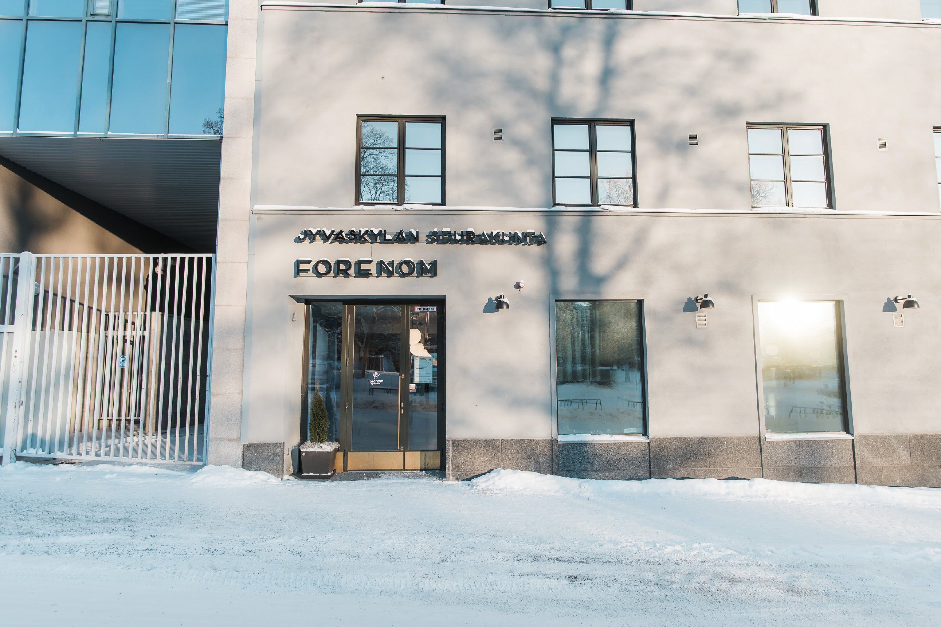 A building with a sign reading "JAVSKYLAN SERAKUNTA ERENOM" and a glass entrance.
