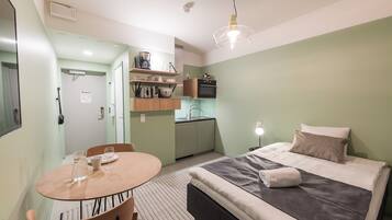 Una habitación pequeña con cama, mesa de comedor y kitchenette.