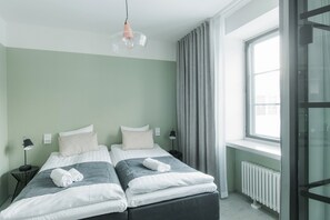 A twin bedroom with two beds, a window with curtains, a radiator, and a pendant light. - Forenom Aparthotel Jyväskylä (Jyväskylä)