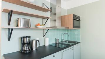 A modern kitchen with wooden shelves, a stainless steel toaster, a coffee maker, and a sink.
