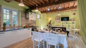 A kitchen with a central island, white cabinetry, and a dining area with a table set for four. - Ai Due Cuori 4, Emma Villas (Capannori)