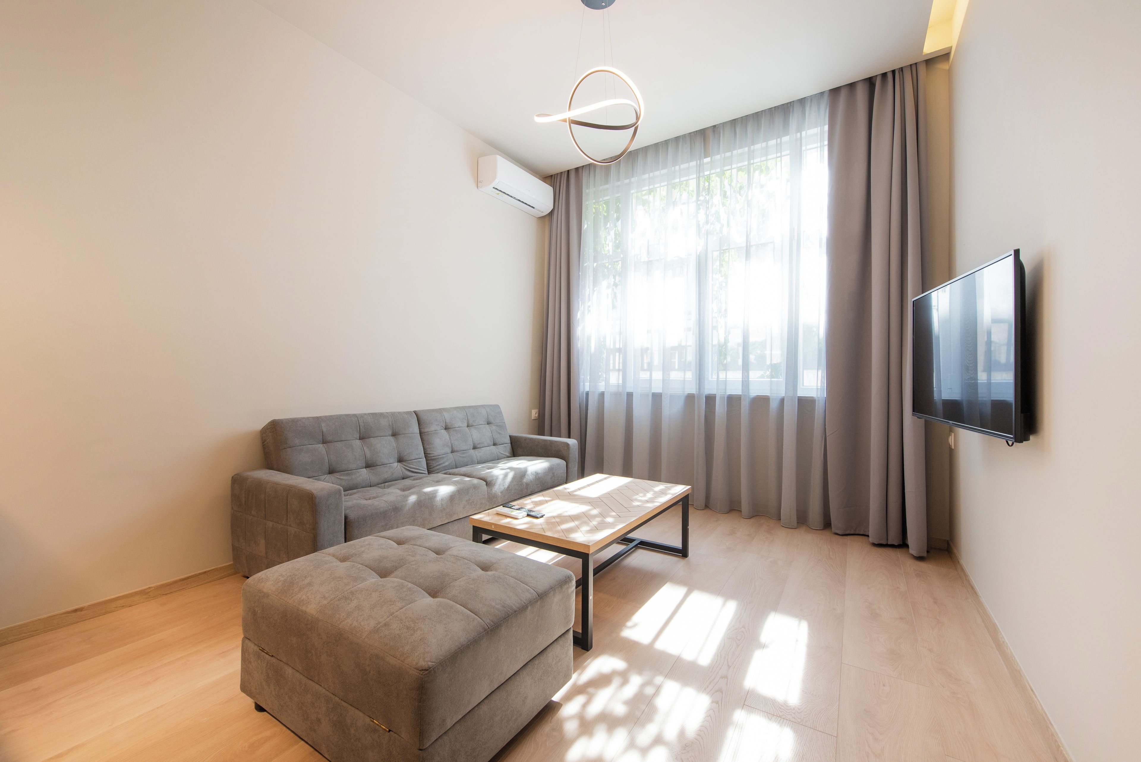 A modern living room with a sofa, ottoman, and a coffee table.