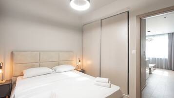 A hotel room with a large bed, bedside tables, a wardrobe, and a view of the adjacent room.