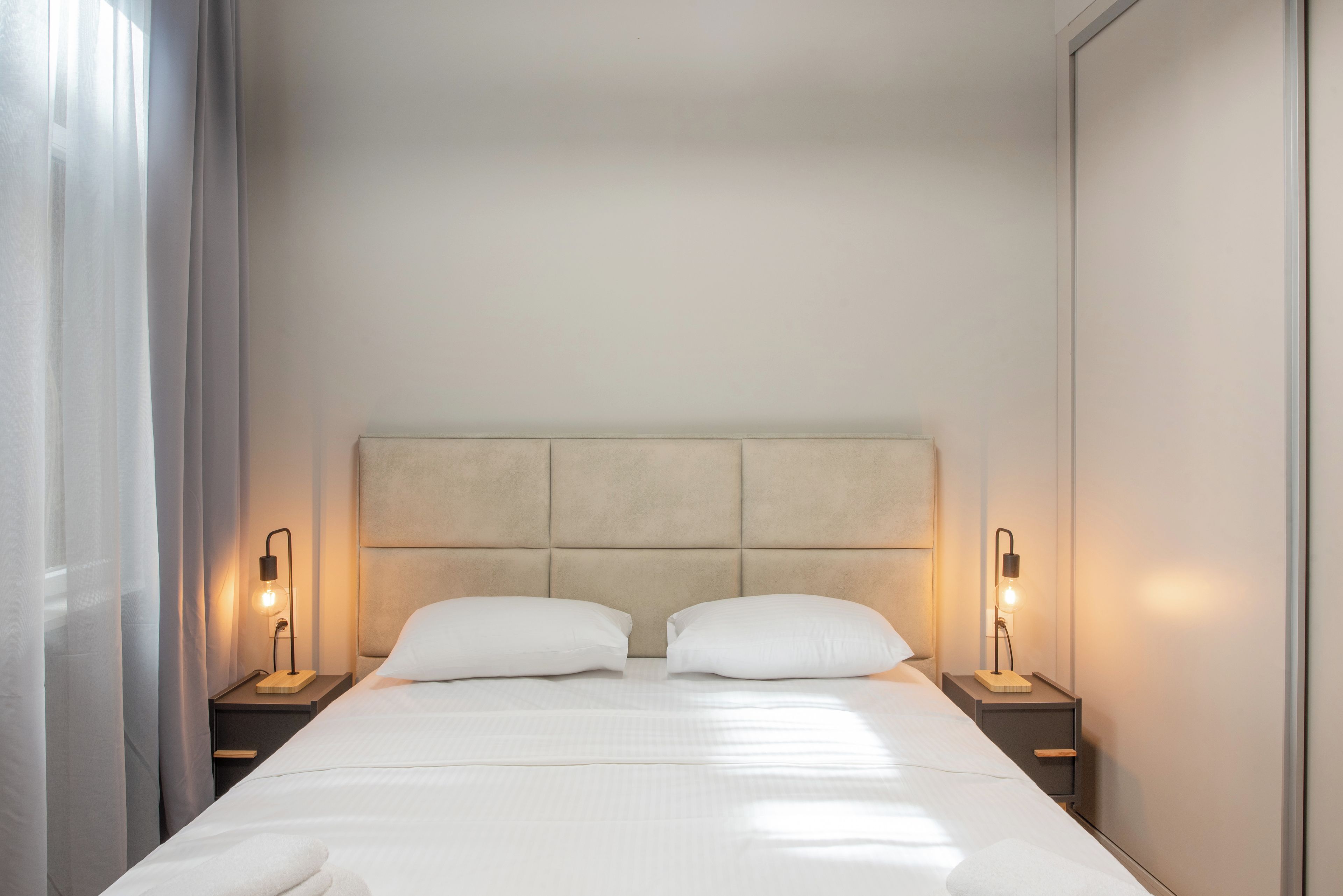 A hotel room with a large bed, two bedside tables, and a headboard.