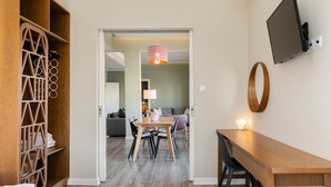 Une chambre d’hôtel comprenant une armoire en bois, un bureau, un lit et un coin repas avec une table et des chaises.