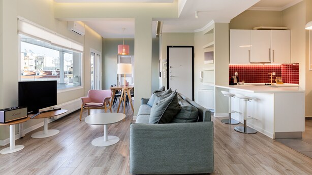 Un salon moderne avec un canapé gris, un téléviseur et un coin repas comprenant des chaises et une table.