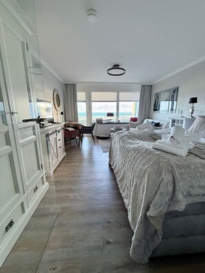 A bedroom with a large bed, a desk, and a view of the sea. - Haus am Meer App. 034 <br>"Togetherness by the sea" (Westerland)