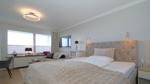 A modern bedroom with a large bed, a desk, and a chair. - Haus am Meer App. 034 <br>"Togetherness by the sea" (Westerland)