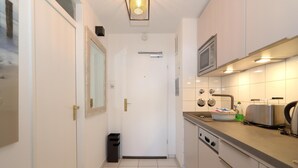 A narrow kitchen with white cabinets, a microwave, and a toaster on the countertop. - Haus am Meer App. 034 <br>"Togetherness by the sea" (Westerland)