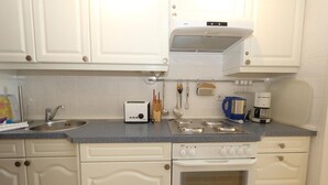 Cuina amb armaris blancs, una rentatges de vidre, torradora, bullidor i cafetera.